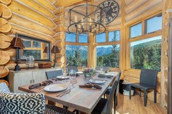 The Villas at Tristant 225 dining area features a rustic wooden table set for a meal, set against a backdrop of natural light and scenic mountain views.