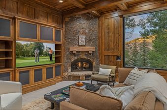 A living room with a fireplace and a large window overlooking a mountain landscape.