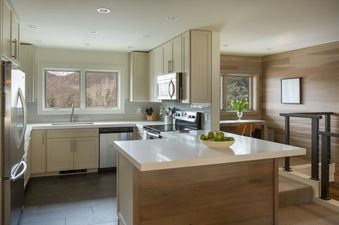 A modern kitchen with white cabinets, stainless steel appliances, and a large island with a wooden countertop.