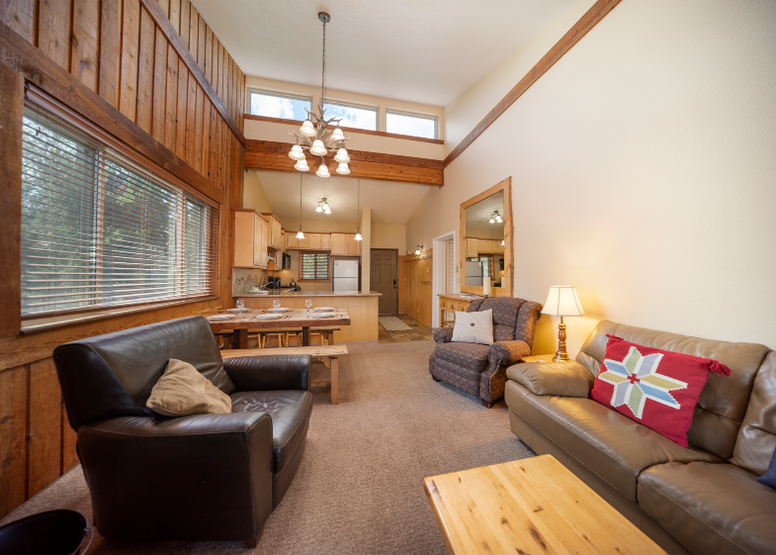 The living area of Beaver Village 1134 features comfortable seating, a dining area, and a glimpse of the kitchen, all illuminated by natural light.