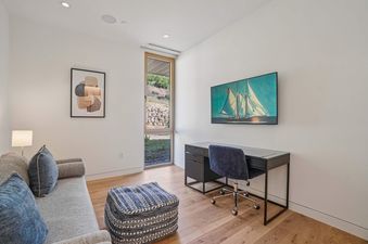 An office area in Founders Place 2302 with a desk, chair, and sofa, accented by a nautical painting and abstract art.