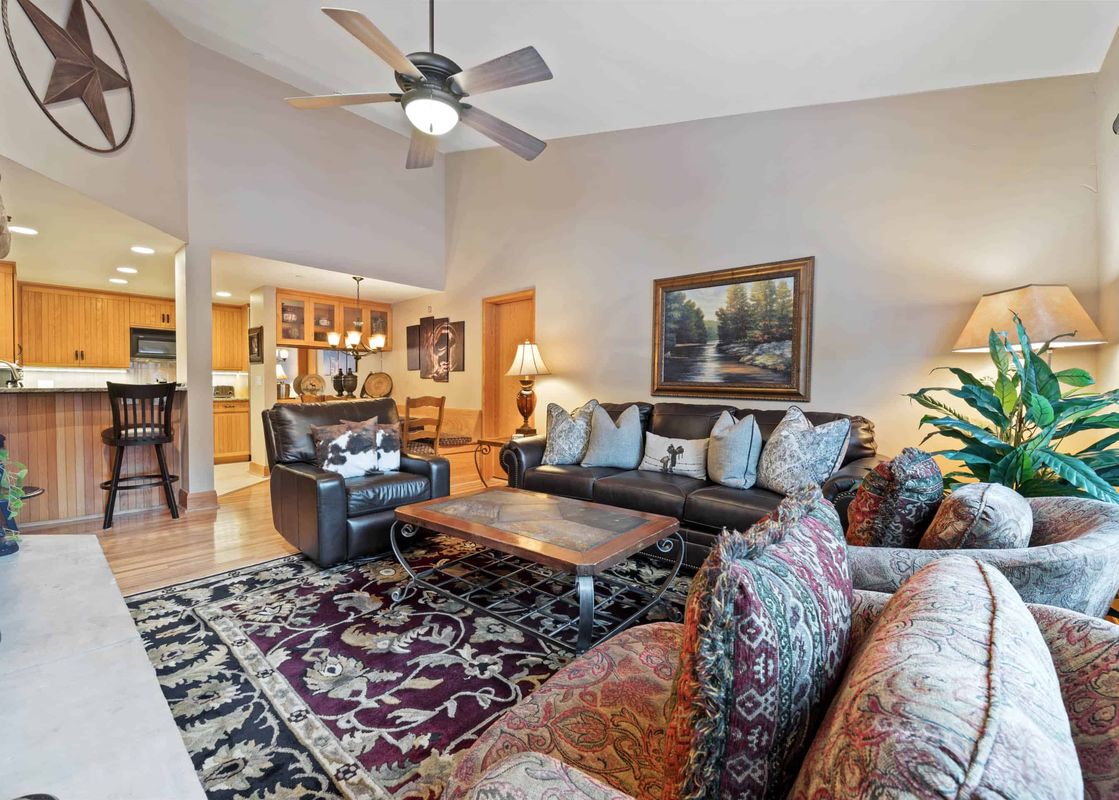 A cozy living room in The Charter B4305 with dark leather furniture, a patterned rug, and a landscape painting on the wall.