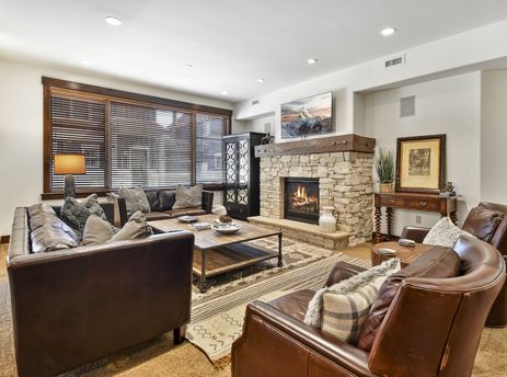 A cozy living room at Silver Star 4102 with brown leather furniture, a stone fireplace, and a large flat-screen TV.