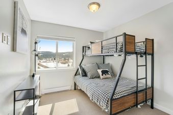 A cozy bedroom with a bunk bed, checkered bedding, and a large window offering a view of a snowy landscape.