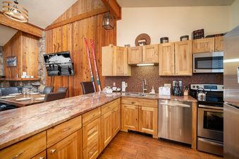 The Beaver Village 2032 2B 2B features a fully equipped kitchen with modern appliances and natural wood cabinetry.