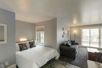 A cozy studio apartment at the Blue Mesa 20a with a queen bed, a sofa, and a balcony with a snowy view.