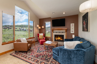 The living room at 2002 Lupine Lane features a cozy fireplace, comfortable seating, and large windows with scenic views.