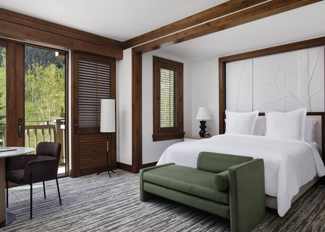A luxurious bedroom at the Four Seasons Mountain Side Room featuring a king-size bed, elegant furnishings, and a balcony with a scenic mountain view.
