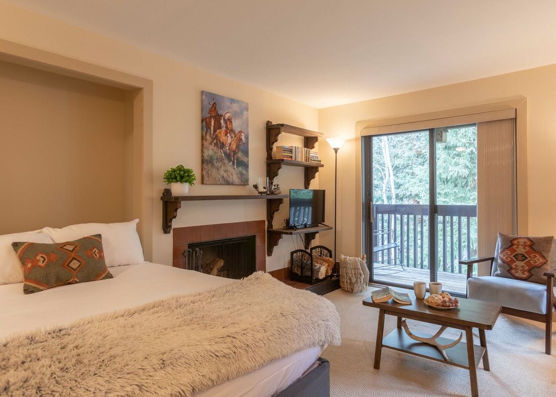 A cozy studio bedroom in Sleeping Indian W12 with a fireplace, private balcony, and seating area.