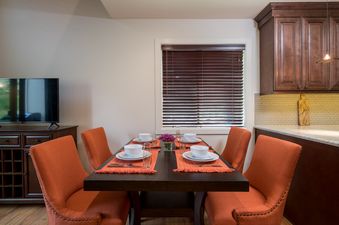 A dining table set for four with orange chairs and a television in a modern dining area at Indian Springs.