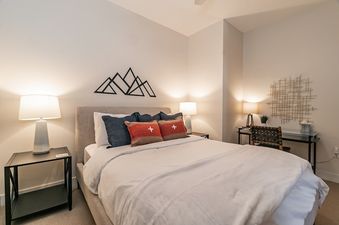 A cozy bedroom at Hideaway Haven featuring a queen bed, warm lighting, and a small desk workspace.