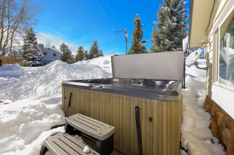 The hot tub at 45 Idelwild is surrounded by snow on a sunny winter day.
