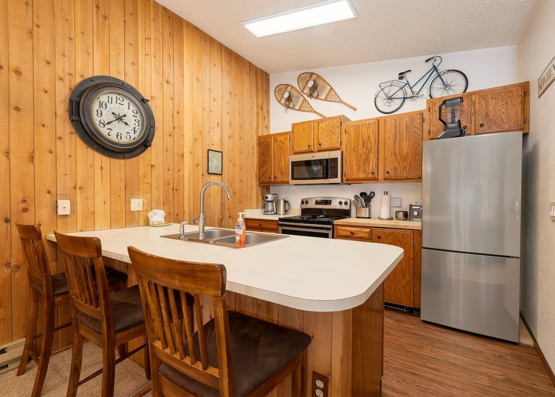 The kitchen at Silverado II Unit 334 features a central island with a double sink, wooden cabinetry, and modern stainless steel appliances.