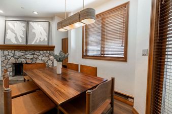 The dining room at Strawberry Park 305 features a long wooden table, comfortable leather chairs, and a stunning stone fireplace.