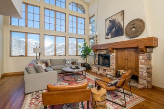 A living room with a sectional sofa, a large fireplace, and a view of the mountains.