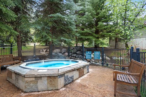 Outdoor community hot tub area at Castle Peak Close with surrounding trees and benches.