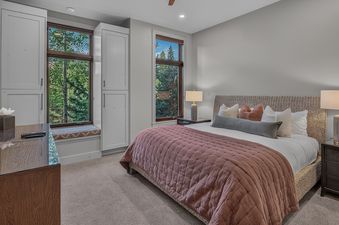Inviting bedroom at Moose Meadows Reserve featuring a plush bed, built-in cabinets, and large windows with serene views of surrounding pine trees.