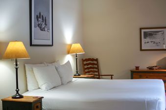 A cozy bedroom with a queen bed, warm lamps, and a wooden rocking chair.