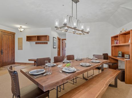 A spacious dining area with a long wooden table, set with place settings, and seating for multiple guests, including leather chairs and a wooden bench.