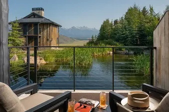 A private balcony of The Grand Reflection Suite overlooking a pond and mountains.
