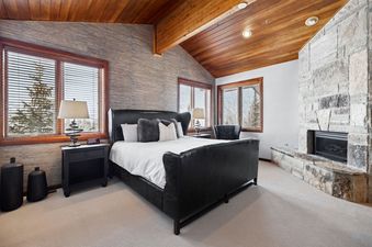 A master bedroom at Deer Valley Double Eagle with a black leather sleigh bed and a stone fireplace.