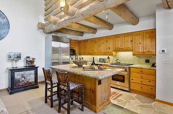 Pine Inn 1 at Trails End Lodge's kitchen features wood cabinets, granite countertops, and stainless-steel appliances.