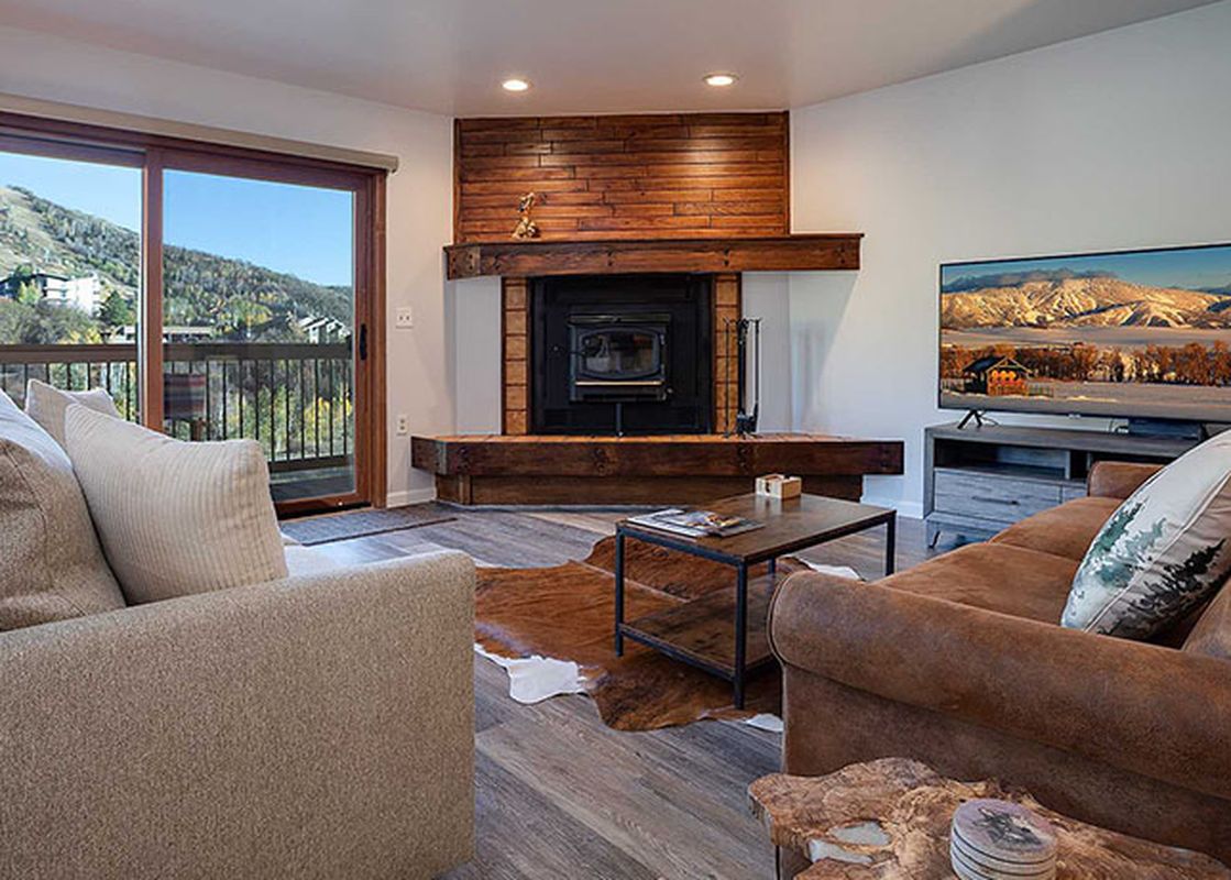 A cozy living area at the Ranch at Steamboat RA605 features comfortable sofas, a stone fireplace, and a large window with scenic outdoor views.