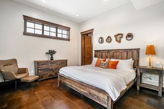 Rustic bedroom at Granby Ranch Lodge featuring a wooden king-size bed, a matching dresser, and a comfortable leather armchair.