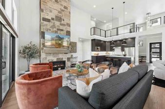 A modern living room with a fireplace, large windows, and a view of the mountains.