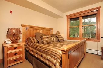 A cozy bedroom in Redhawk Townhome 3 Bedroom with a comfortable bed, nightstand, and a window offering a view of the outdoors.