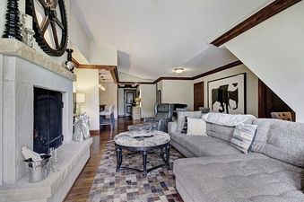 The living room of Ritz Carlton 2BR Valley View with a stone fireplace, plush furniture, and a view of the hallway.