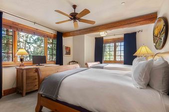 A bedroom with two beds, a window with an exterior view, and a wooden ceiling beam.