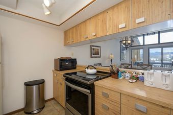 A well-equipped kitchen with wooden cabinetry, stainless steel appliances, and a mirrored backsplash offers mountain views.