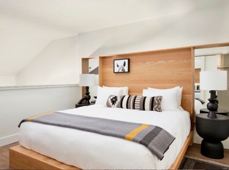 Modern loft bedroom in the Gravity Haus Jackson Hole Suite with a king bed, custom wood headboard, and black bedside lamps.
