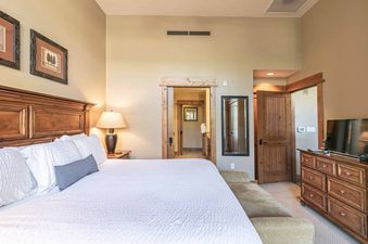 A bedroom with a king-size bed, a wooden headboard, two nightstands, and a TV.