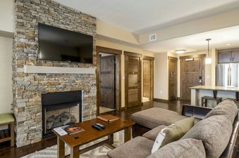 Trailhead Lodge 4115 features a spacious living area with a stone fireplace, a large sectional sofa, and a coffee table.