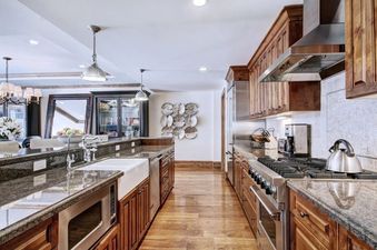 A modern kitchen with wooden cabinets, stainless steel appliances, and a granite countertop.