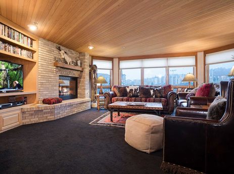 A cozy living room at Chateau Chamonix CX122 with a fireplace, comfortable seating, and large windows offering an exterior view.