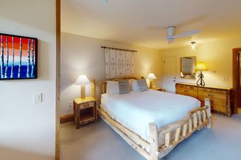 A bedroom with a king-size bed, a wooden dresser, and a nightstand.