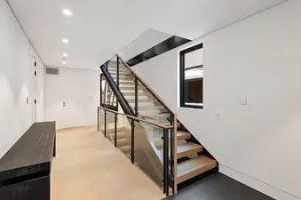 A modern staircase with glass railings and wood steps in Maison Cornet.