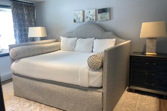 A hotel room with a large, comfy bed and a side table with a lamp.