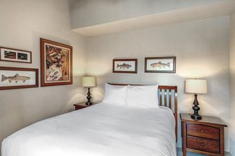 The Racquet Club 60's bedroom features a bed with white linens, wooden nightstands, and fishing-themed art.