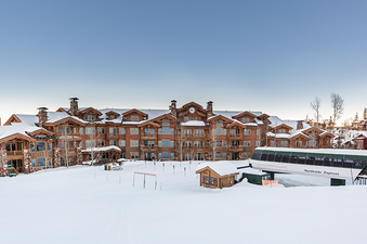Exterior view of the Grand Lodge at the base of the mountain with the Northside Express ski lift in the foreground.