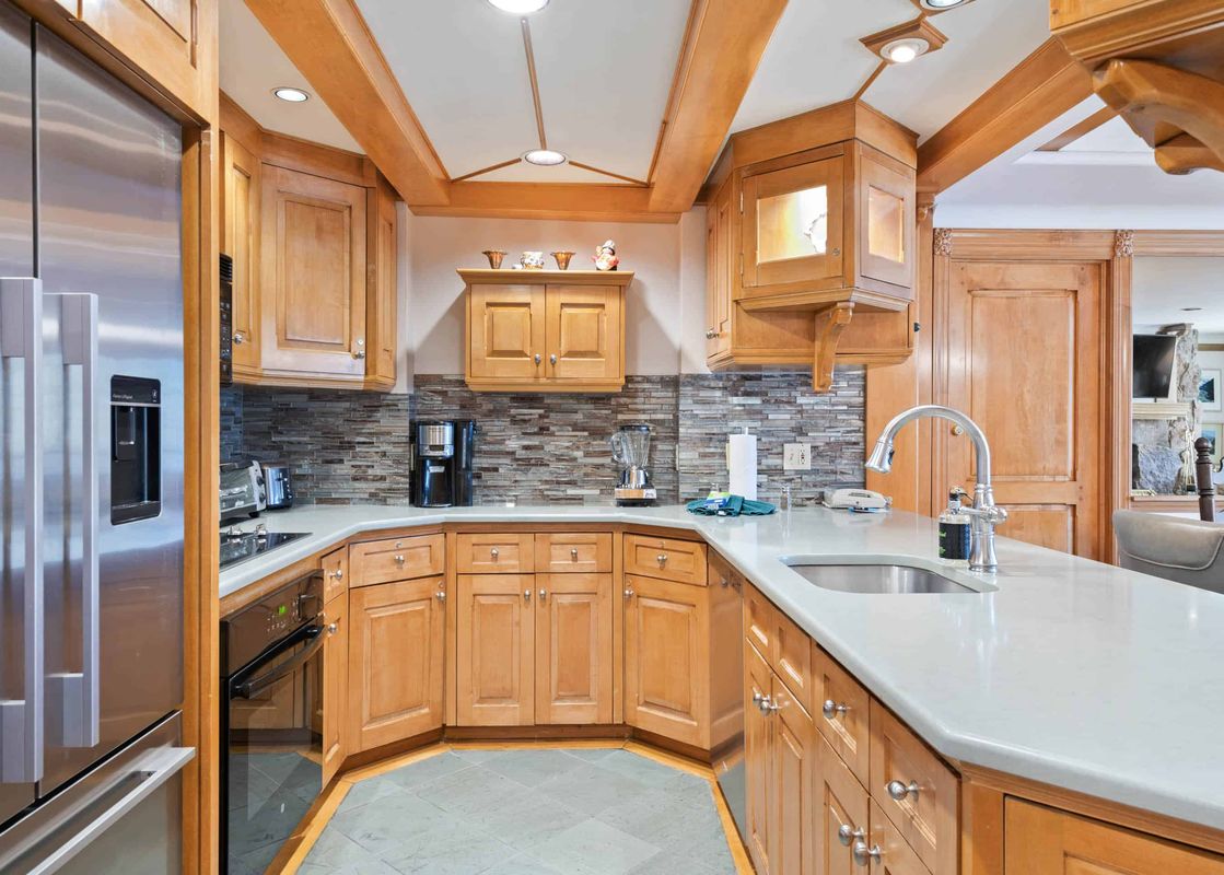 A modern kitchen in Lodge Tower 387 3BR with light wood cabinets, light countertops, and a tiled backsplash, featuring stainless steel appliances.