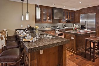 A spacious kitchen with rich wood cabinetry, granite countertops, and stainless steel appliances is seen.