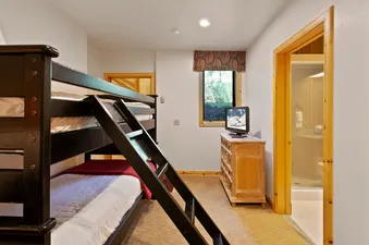 The bedroom at Trails End Lodge 18 features a bunk bed with a white comforter and a red blanket.