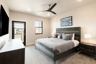 Modern bedroom with a gray wooden king bed and glass door to the balcony in Mayflower Lakeside 45-203.