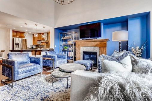 A living room with a fireplace, blue walls, and a large couch.