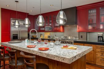 The kitchen at Cougar Mountain One Steamboat Place 501 features rich red cabinetry, stainless steel appliances, and a spacious island with bar seating.