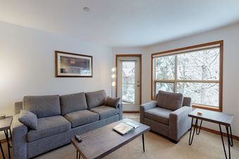 The living area of Aspens on Blackcomb Unit 443 with a snow-covered outdoor view.